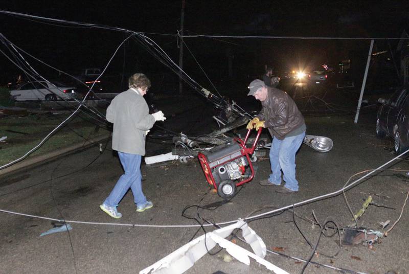 A man and woman try to wheel a portable generator through a maze of downed wires along Center Street following a tornado on Tuesday, Feb 28, 2017 in Naplate.