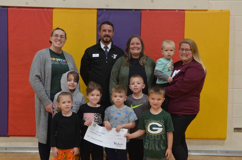 Andy McFarlane (second from left) and Heather Grobe (right), along with children enrolled at the YMCA childcare center, accept a $1,000 grant Friday, Oct. 6, 2023 from Ainsley Ports (left) and Lisa Sandrock, both with Starbucks.