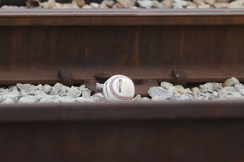 A foul ball sits on the tracks at the Metra train yard adjacent to the Joliet Central field as the Steelmen host Bolingbrook on Tuesday, March 21st. 2023.