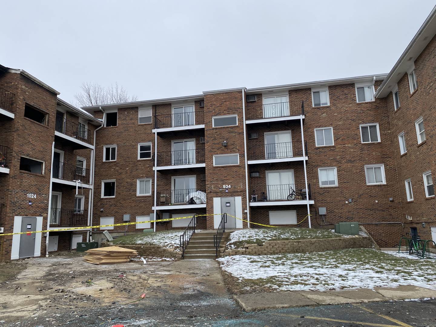 The rear of 1024 W. Hillcrest Drive, is taped off to residents and passersby on Monday, Dec. 23, 2024, after the City of DeKalb condemned the building less than 24 hours following a major fire on Sunday, Dec. 22, 2024. The fire displaced an estimated 60 residents in the three-building complex. Debris and charred remnants of the building lay scattered around the parking lot Monday.