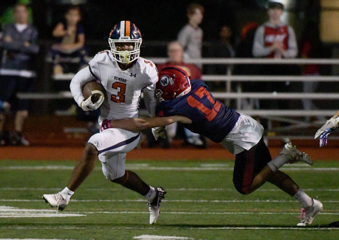 Oswego's Cameron Grays (3) gains some yards before being tackled by West Aurora's Austin Pierce (17) during a game in Aurora on Friday, October 8, 2021.