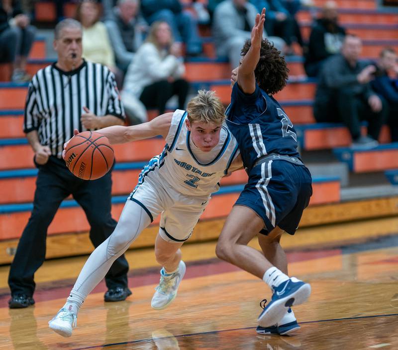 Downers Grove South's Will Potter (left) drives to the basket against Oswego East's Bryce Shoto during the hoops for healing basketball tournament at Naperville North High School on Monday, Nov 21, 2022.