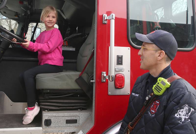 Mirren McGuirre of Ottawa, smiles as she sits behind the wheel of a Ottawa fire engine as firefighter Michael Williams watches during story time on Thursday, April 10, 2025 at the Reddick Library in Ottawa.
