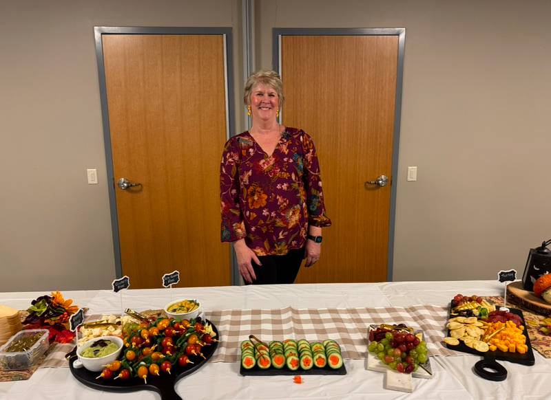 Susan Glassman, Nutrition and Wellness Educator, stands in front of the charcuterie board she’ll be teaching others to create