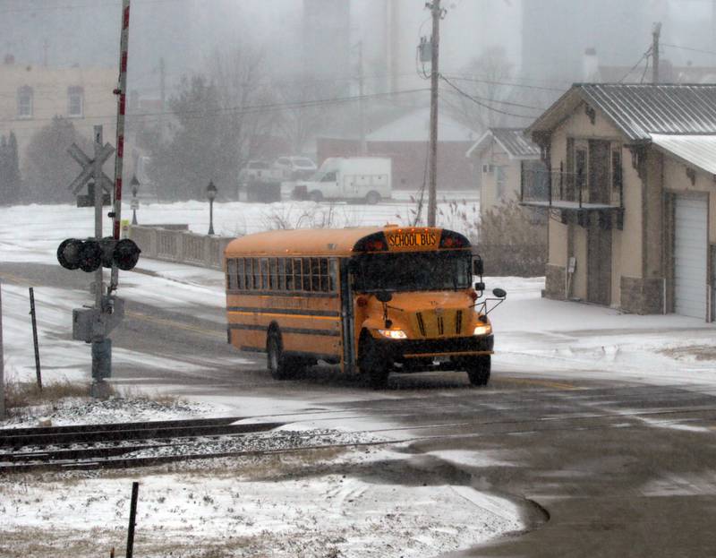 A school bus drives in the snow as it crosses the train tracks in downtown Utica on Thursday Feb. 17, 2022.