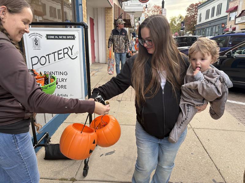 Deanne Ferguson, left, hands candy to Christiana Bivens and Thaddeus McQueen, 1, of Woodstock during Halloween on the Square in Woodstock Oct. 31, 2025.