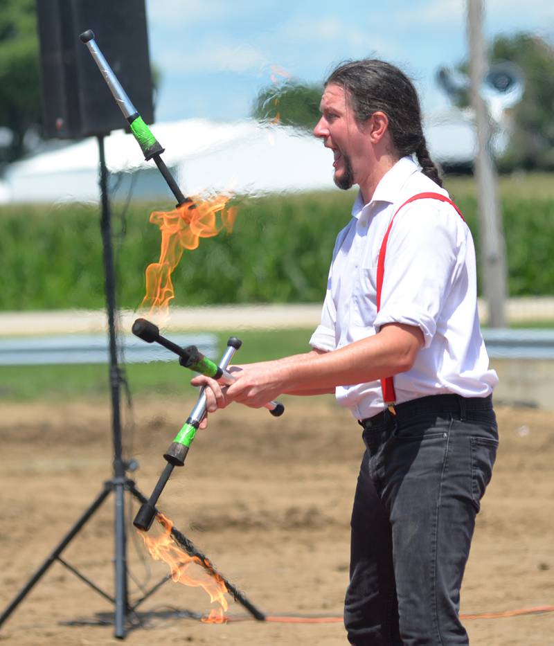 A performer with the Cincinnati Circus Thrill Show juggles fire wands at the Lee County Fair on Sunday, July 30, 2023.
