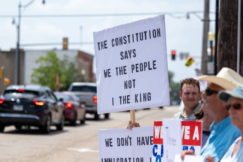 Protesters hold signs and chant at the “No Kings” protest as cars drive down north Main Street on Saturday, June 14, 2025 at Rotary Park in Princeton.