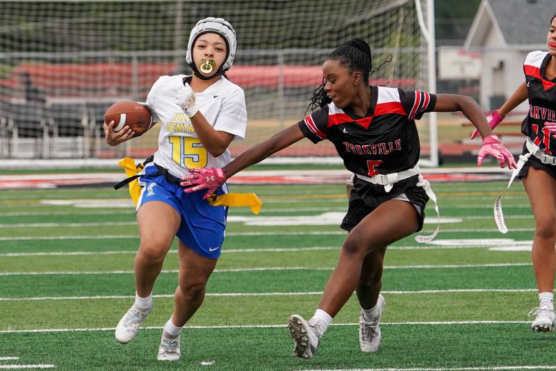 Joliet Central's Victoria Godinez (15) carries the ball on a keeper against Yorkville's Cassia Bonga (5) during a flag football game at Yorkville High School on Monday, Sep 23, 2024.