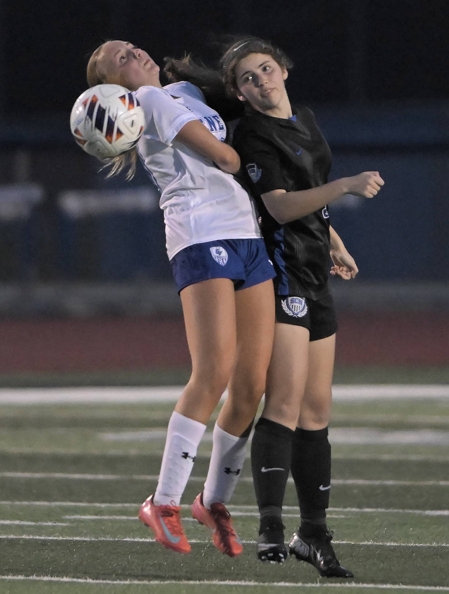 Geneva’s Alexis Guess and St. Charles North’s Hannah Stone, right, battle for a header in a girls soccer game in St. Charles on Thursday, Apr. 9, 2026.