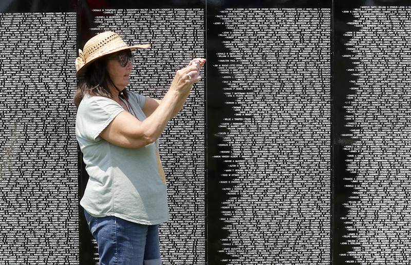 Kathy Cole of Kingsman, Arizona, photographs the Vietnam Traveling Memorial Wall at the VFW Post 4600 in McHenry, on Friday, July 14, 2023. The 3/5 scale wall Will be at the post and open to the public until Sunday evening and will hold an opening  ceremony at 10 a.m. on Saturday.