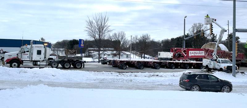 Crews raise wires and traffic signals at the state Route 64 intersection with Daysville Road, east of Oregon, on Monday, Dec. 8, 2025 as one of the large turbines headed for Constellation's Byron generating station is transported. From Route 64, the tractor and trailer traveled east to German Church Road and then north to the nuclear power plant.