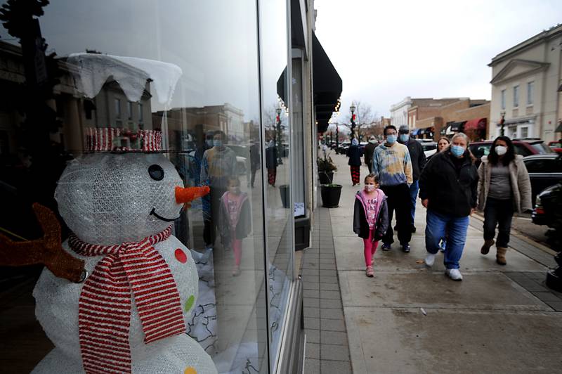 A snowman peers out of a shop window as people shop Saturday, Nov, 27, 2021, during Small Business Saturday in downtown Crystal Lake.