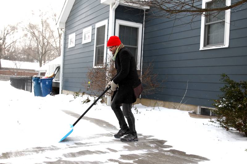 Andrew Hamilton, who is visiting from Southern England, shovels the driveway of a home in Downers Grove as temperatures dip below zero on Friday, Dec. 23, 2022.