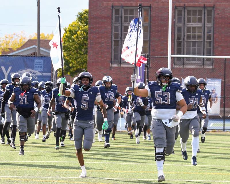 Chicago Hope Academy teammates Justin Houston (5) and Levi Mallette (53) lead the team onto the field before the start of the first round of 3A playoffs on Saturday Nov. 1, 2025; while taking on IC Catholic held at Altgeld Park in Chicago.