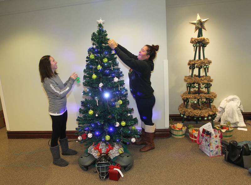 Amanda Reed and Felicia Salazar, both of Round Lake hang ornaments on the Avon Township Youth Baseball & Softball tree which will be on display in the Giving Trees exhibit at the Grayslake Heritage Center & Museum.