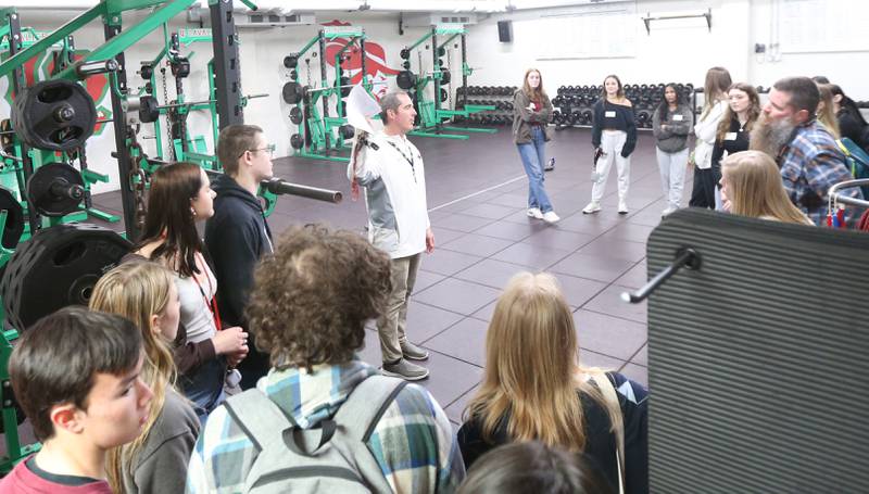 Mr. Patrick Carney, (center) talks to Naperville Central students while touring the L-P weight room on Tuesday, April 18, 2023 at L-P High School. Mr. Carney organized the student swap with Naperville Central. L-P students will visit Naperville Central on Thursday.