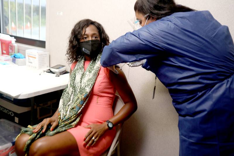 Illinois Department of Public Health director, Dr. Ngozi Ezike, is administered the Pfizer-BioNTech Covid-19 booster vaccination by site manager Mary Barkho at the State of Illinois Community Drive-Thru Vaccination and Testing Site in Aurora on Thursday, Oct. 28, 2021.