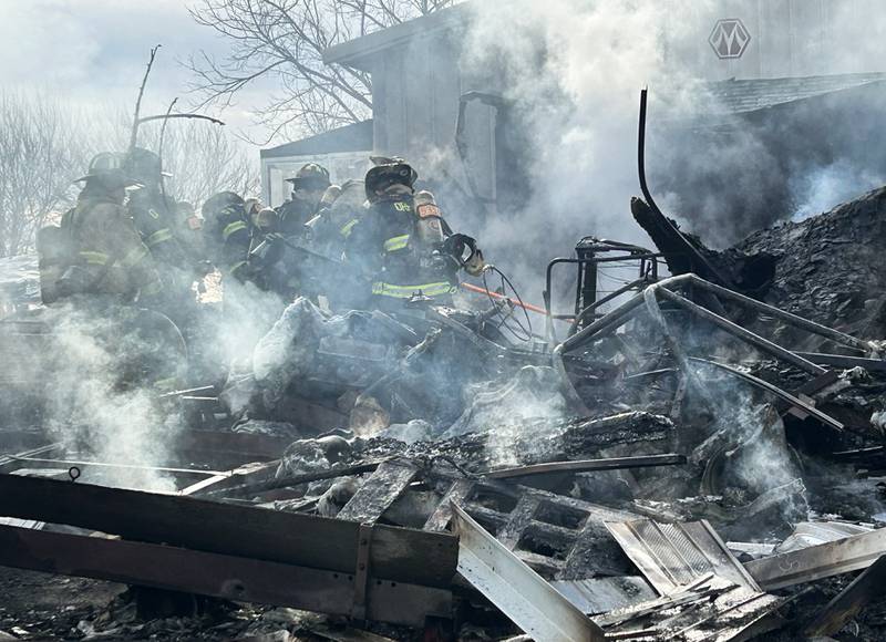 Firefighters look for hot spots in a charred garage following an early evening fire at 6727 W. Henry Road, southeast of Polo, on Wednesday, March 26, 2025. Several departments responded to the fire at the rural residence. In addition to a camper, one vehicle and other items located inside and around the garage were destroyed. No injuries were reported.