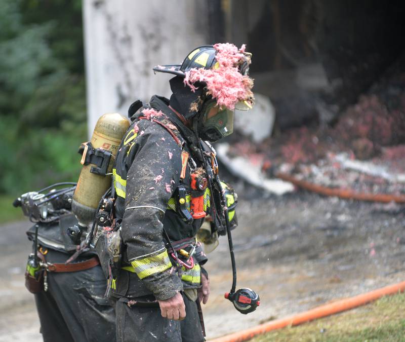 Pieces of pink insulation cover an Oregon firefighter's helmet as he waits to have  his oxygen tank replaced while battling a fire at 540 E. Elizabeth Road, southeast of Oregon, on Wednesday, Aug. 20, 2025.