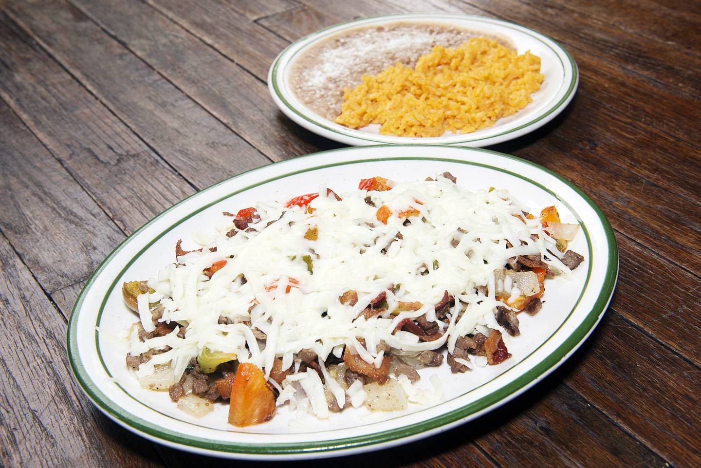 On the menu are the staples, such as burritos, tacos and enchiladas, but other dishes, such as allambre — chopped steak cubes, bacon, onion and bell peppers topped with chihuahua cheese, shown here with a side of rice and beans.