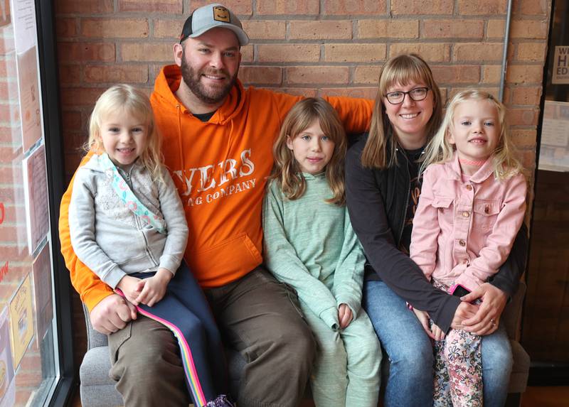 Steve and Megan Byers, co-owners of Byers Brewing Company, with their daughters Emmy, (left) 4, Lily, 9, and Kennedy, (right) 7, Friday, Jan. 6, 2023, in the window of the brewery and taproom in DeKalb. Byers is planning an expansion of its operations to include another location,  216 N. Sixth St., in DeKalb for production only.