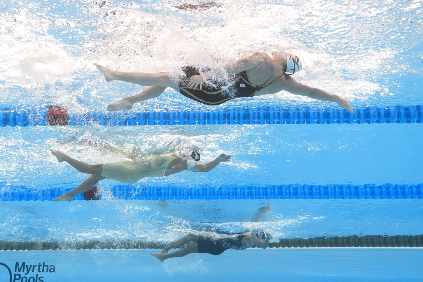 Valerie Tarazi of Palestine, top, Masniari Wolf of Indonesia, center, and Donata Katai of Zimbabwe compete in the women's 100-meter backstroke heat at the World Aquatics Championships in Doha, Qatar, in Feb. 2024.