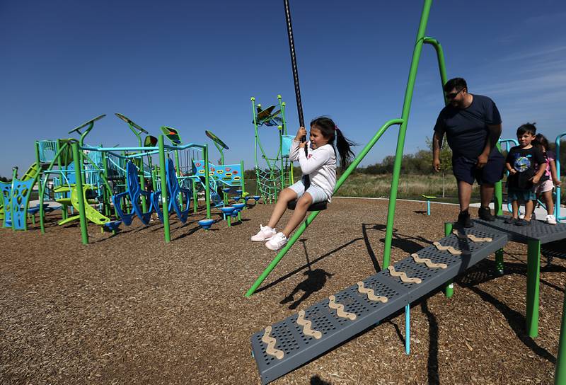 Michael Flores, watches as his daughter, Elyana, rides the zip line on Saturday, Sept. 27, 2025, while playing at Crystal Lake Parks District’s new Lakewood Meadows Park.