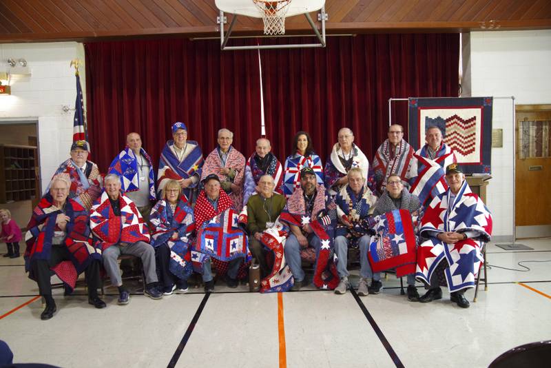 (Front from left) Ralph Sterrett, Clyde Johnson,Jill (John) Newbold, Frank Matsko, Jim Hoskins, Ronald Tardio, Jr, Brian Trost, Don Redd, Ronald Tardio, Sr., (back from left) Mack McKanna, George Krasnican, Jim Olmsted, Harold Marshall, John Kudla, Bridget Kelly, Lee McCumsey, Dennis Hatzer and Bryan Phelan receive Quilts of Valor on Sunday, Nov. 12, 2023, at Holy Trinity Church Fellowship in Streator.