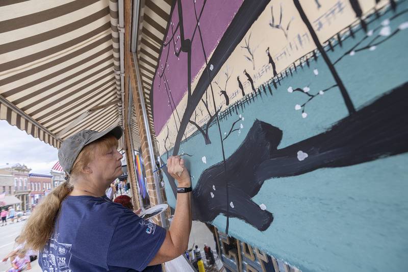 Linda White of Pennsylvania decorates a store window while in the area visiting a friend for Morrison’s Paint the Town Saturday, Sept. 20, 2025.
