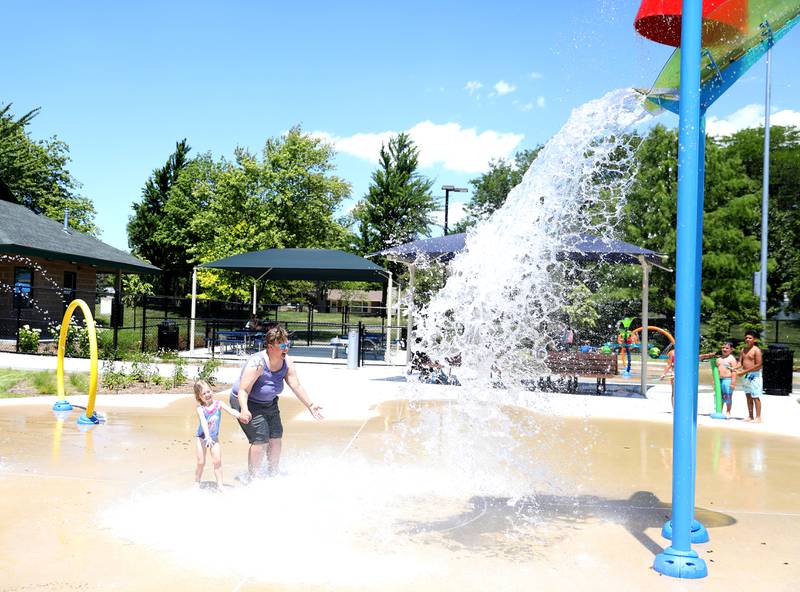Jewel Gateley holds onto 3-year-old Alessandra Sperry as water is dumped from a towering bucket at the Downers Grove Park District’s Adventure Falls Sprayground at McCollum Park on Friday, June 14, 2024.
