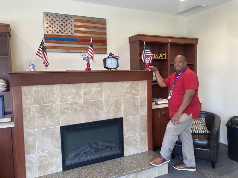 Hope Manor Joliet Housing Coordinator Dontane Farmer stands by the fire place in the lobby of Hope Manor.