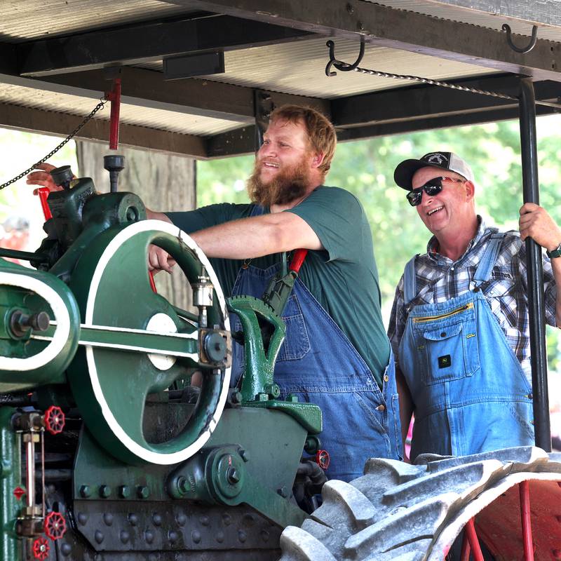Austin Druien (left) and his dad John, from Holcomb, honk their whistle as they drive their 1914 Case 50 horse power steam tractor in the parade Thursday, Aug. 8, 2024, during the 67th annual Sycamore Steam Show and Threshing Bee at Taylor Marshall Farm.