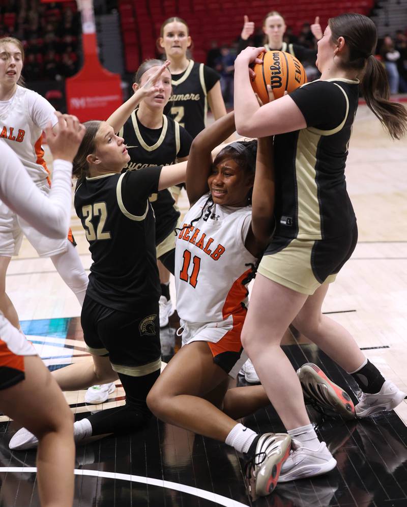 DeKalb's Johnna Patrick tries to hold onto the ball between Sycamore's Quinn Carrier (left) and Norah Chami Friday, Jan. 30, 2026, during their game in the FNBO Challenge in the Convocation Center at Northern Illinois University in DeKalb.