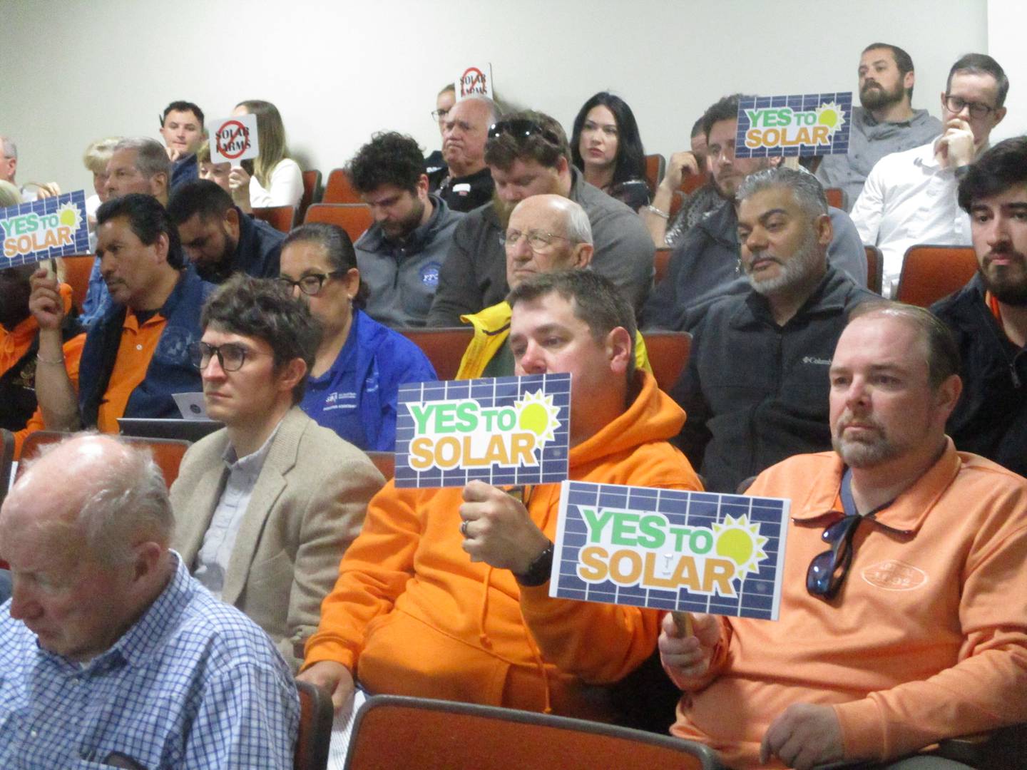 Supporters of the Pride of the Prairie solar project hold up signs at the Will County Board meeting on Thursday at the Will County Office Building in Joliet. May 21, 2026
