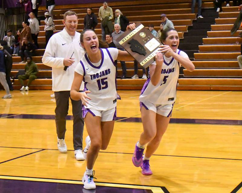 Downers Grove North teammates Adysen Fanta (15) and Campbell Thulin (5) run to join the rest of the team with the 4A regional championship plaque after taking the win over St. Laurence on Thursday Feb. 19, 2026, held at Downers Grove North High School.