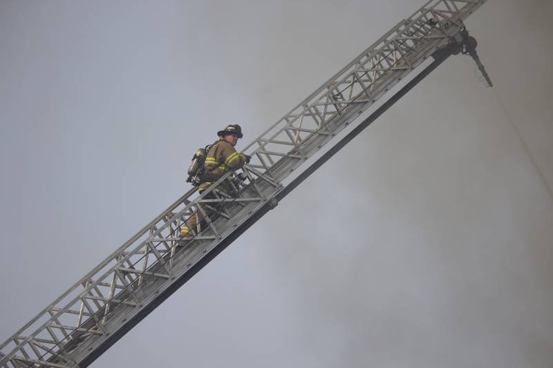 A Joliet firefighter climbs a ladder as part an effort to fight a fire at an apartment building on Tuesday, June 10, 2025, near Essington Road in Joliet.