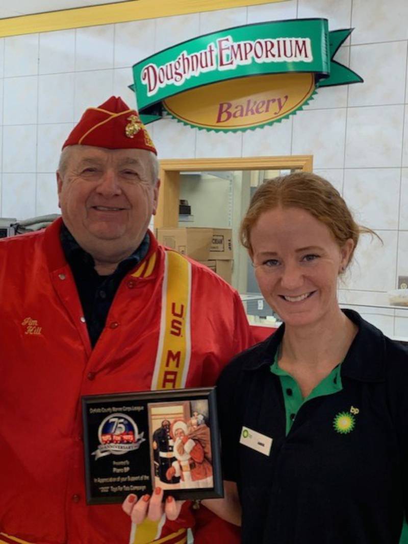James Hill, DeKalb County Marine Corps League Detachment 847 representative, presents a Toys for Tots thank you plaque to Abbie Luecht, manager at the Plano BP.