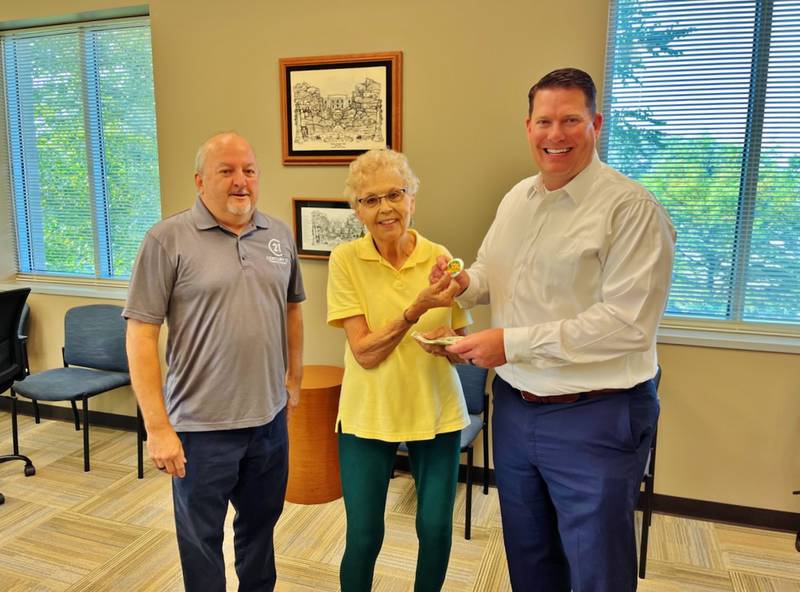 Morris Mayor Chris Brown (right) purchases button number 2022, the first sold this year, from board members Sue Morse (center) and Jim Maskel (right).