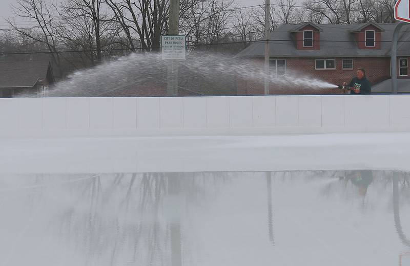 Jim Duncan sprays water on top of The Schweickert Arena ice rink on Tuesday, Nov. 25, 2025 at Washington Park in Peru. The rink opens this weekend. With the new chiler system, the ice rink is expected to stay open until the end of February 2026.