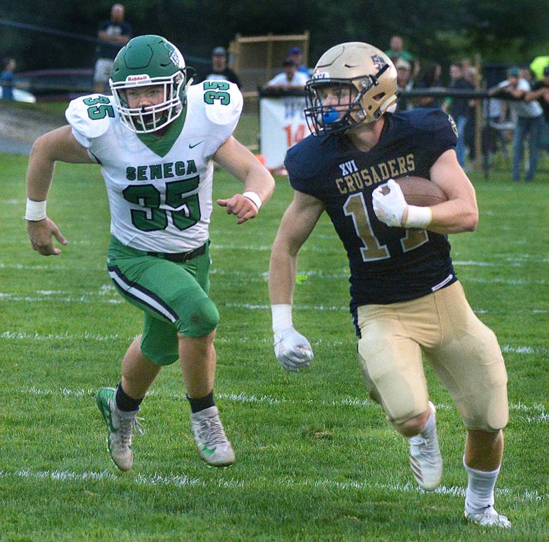 Marquette’s Evan Green (17) skirts around the left end ahead of the pursuit of Seneca’s Myles Mitchell during Friday night’s battle at Gould Stadium in Ottawa. Green contributed 73 yards to the Crusader ground game and kicked five PATs and a 35-yard field goal in a 31-0 MA victory.