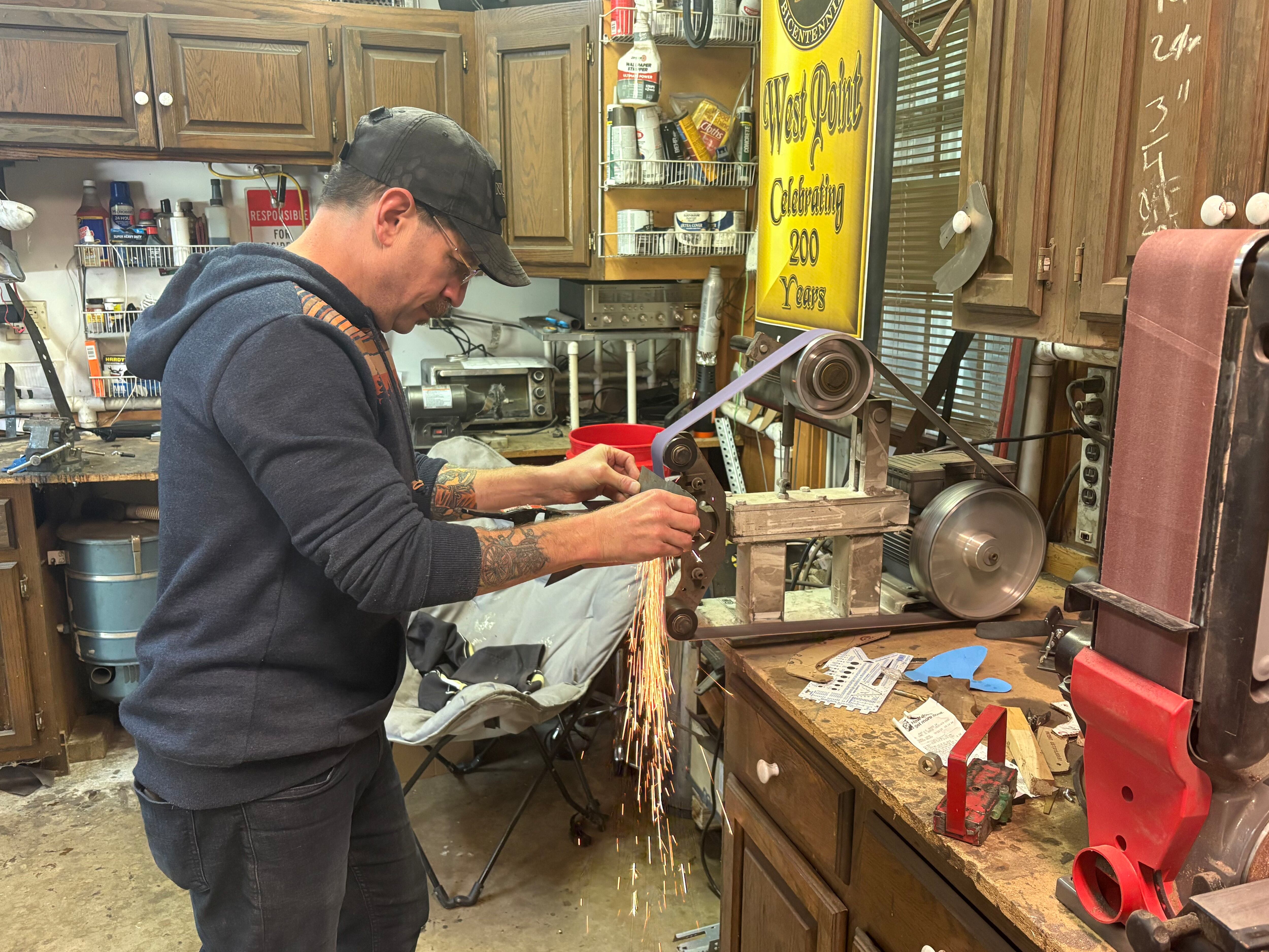 Army veteran Doug Katz shapes a piece of metal into a knife in his garage workshop in Trout Valley.