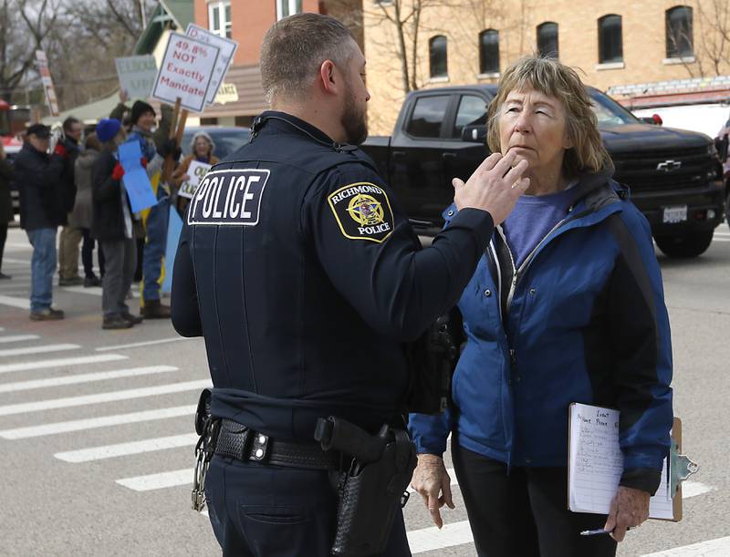 Pat Lawlor talks with a Richmond police officer about crosswalk safety as protesters line U.S. Route 12 in Richmond to protest their discontent with President Donald Trump and his administration's policies on Saturday, April 19, 2025. Over 100, people took part in the Richmond protest. A second rally was held in Harvard later in the day.
