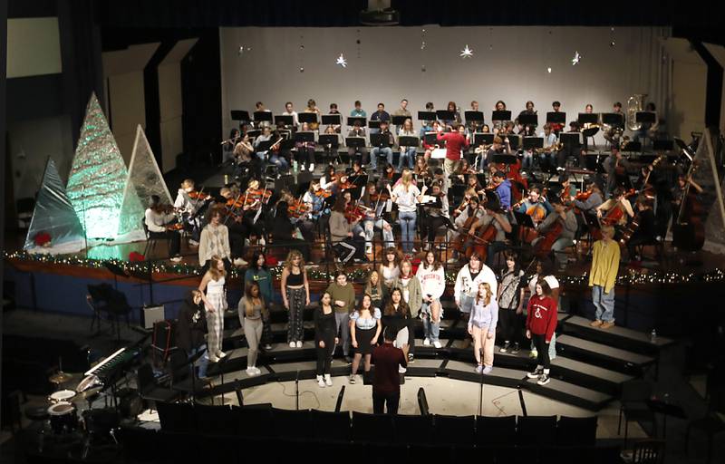 Members of the Woodstock High School band, orchestra and choir perform  “Unknown” composed by Woodstock High School graduate Alex Riak on Thursday, Dec. 7, 2023, during a rehearsal for the school's “Across the Universe” concert.
