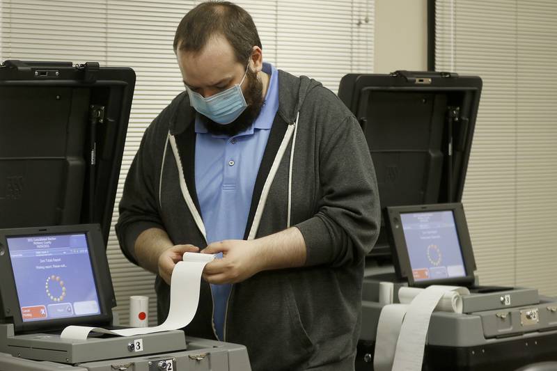 McHenry County information technology resource employee A.J. Degenhardt spools paper receipts from a tabulation machine as he clears the cache of results inside the voting tabulation room at the McHenry County Administrative Building on Thursday, April 8, 2021, in Woodstock.