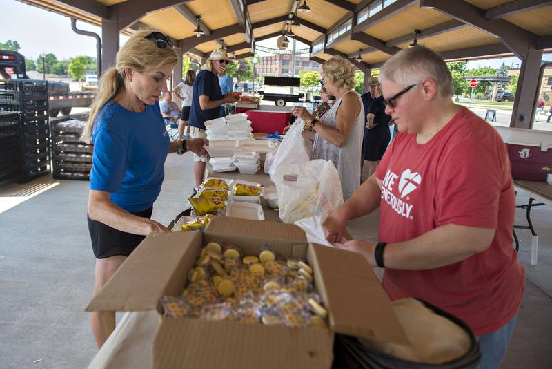 Volunteers pack up chops, a cookie and chips into boxes for the lunches. The meals were marketed as a power lunch and included two ears of Poci's sweet corn and water.