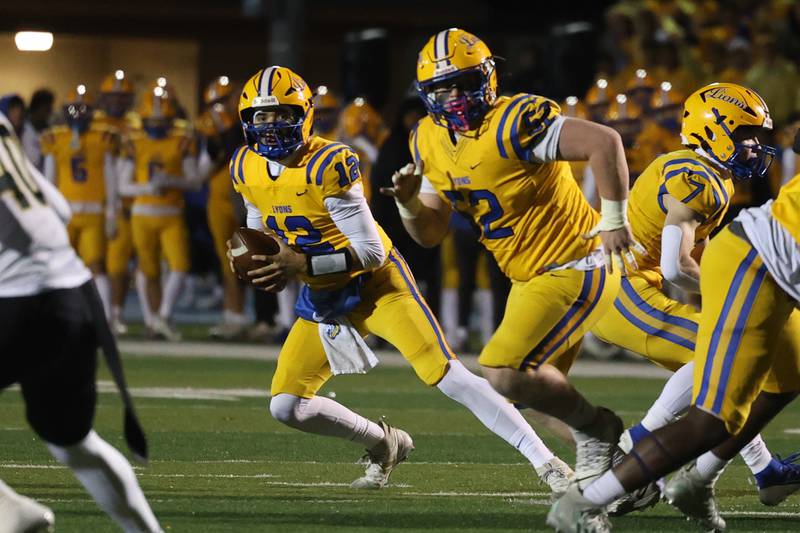 Lyons Township’s Dom Biscotti rolls out to pass under the protection of James Hillman against Joliet West in the first round of the playoffs on Friday, Nov. 1, 2024 in La Grange.