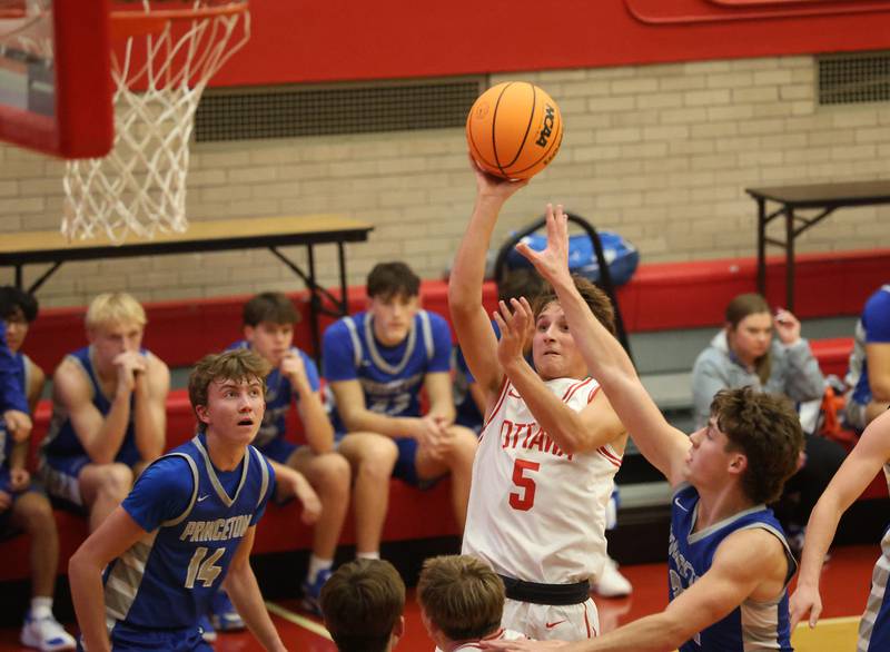 Ottawa's Rory Moore eyes the hoop as Princeton's Ryan Jaegers and Jackson Mason defend the lane during the Dean Riley Shootin' The Rock Thanksgiving Tournament on Monday Nov. 24, 2025 in Kingman Gymnasium at Ottawa High School.