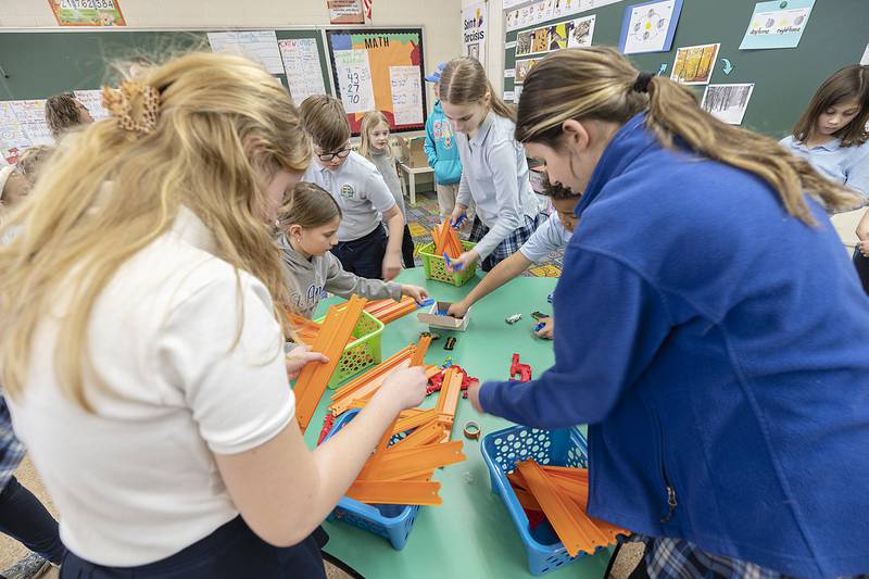 St. Anne’s students pick up materials to build a track for a small car Thursday, March 6, 2025, at the Dixon school. The school held a STREAM (Science, Technology, Religion, Engineering, Art and Math) event to the theme of Force in Motion.