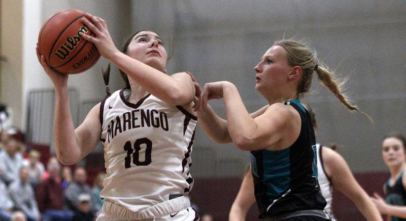 Marengo’s Bella Frohling, left, looks to the hoop against Woodstock North’s Caylin Stevens in varsity girls basketball at Marengo Tuesday evening.